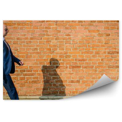 Fototapeta na stenu Kráčajúci muž v obleku na pozadí tehlovej steny